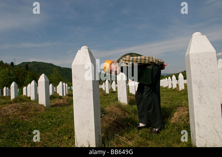 Un musulmano bosniaco si trova tra tombe dei suoi parenti, vittime del genocidio Srebrenica, nel cimitero di Potocari, vicino a Srebrenica, in Bosnia Foto Stock