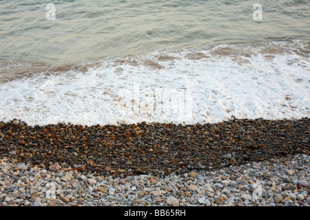 Lavaggio onde su una spiaggia di ciottoli Foto Stock