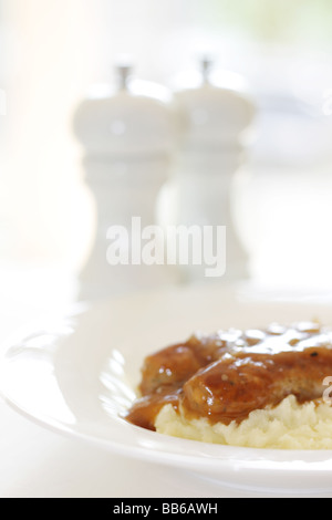 Fresche salsicce di maiale con purè di patate servita su una piastra bianca con n. di persone Foto Stock