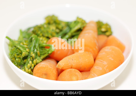 Ciotola di fresco e salutare greggio crudo Baby carote e broccoli contro uno sfondo bianco con un tracciato di ritaglio e nessun popolo Foto Stock