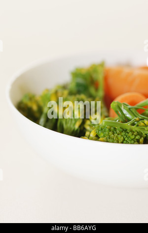 Ciotola di fresco e salutare greggio crudo Baby carote e broccoli contro uno sfondo bianco con un tracciato di ritaglio e nessun popolo Foto Stock