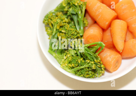 Ciotola di fresco e salutare greggio crudo Baby carote e broccoli contro uno sfondo bianco con un tracciato di ritaglio e nessun popolo Foto Stock