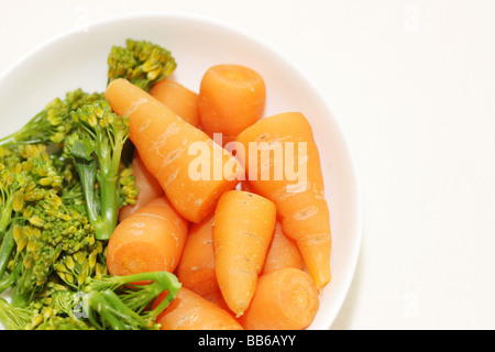 Ciotola di fresco e salutare greggio crudo Baby carote e broccoli contro uno sfondo bianco con un tracciato di ritaglio e nessun popolo Foto Stock