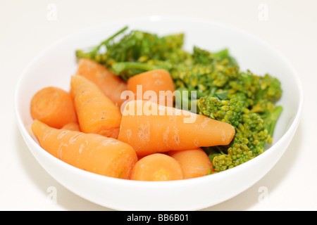 Ciotola di fresco e salutare greggio crudo Baby carote e broccoli contro uno sfondo bianco con un tracciato di ritaglio e nessun popolo Foto Stock