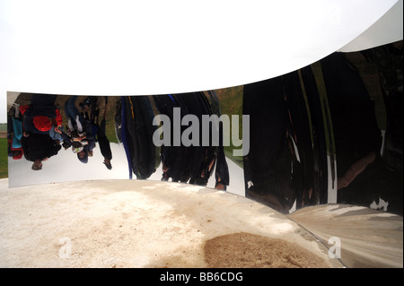 Le persone guardano le loro riflessioni nell'installazione C-Curve di Anish Kapoor su a sud giù per il festival di brighton Foto Stock