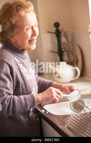 Senior donna lavaggio fino al lavandino Foto Stock