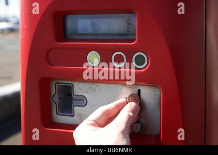 L'uomo mettendo pound coin in pay e display parcheggio macchina nel Regno Unito Foto Stock