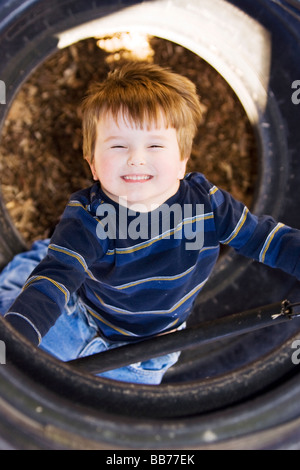 Bambino guardando attraverso il pneumatico al parco giochi - Franklin Park - Brevard, Carolina del Nord Foto Stock