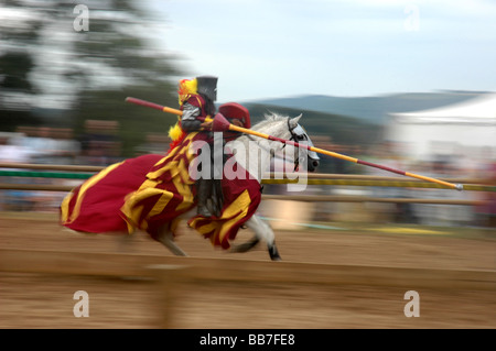 Un cavaliere in armatura cariche su un cavallo bianco in una mostra della giostra medievale a Lulworth Castle Dorset Foto Stock