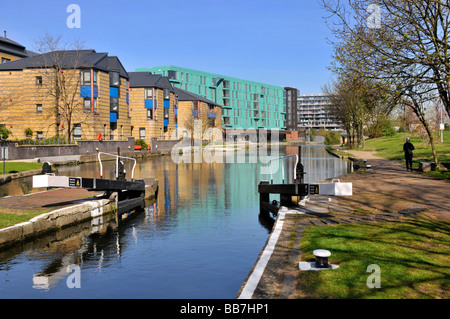 Riflessione invernale nel Regents Canal at Mile End bloccare i sentieri con la Queen Mary University of London edificio moderno design cielo blu soleggiato Inghilterra Regno Unito Foto Stock