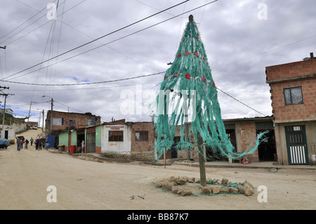 Invecchiamento enorme albero di Natale al vento su una piazza cittadina, baraccopoli di Alto de Cazuca, Soacha, Bogotá, Colombia Foto Stock