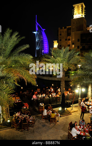 Il ristorante all'aperto presso il Madinat Jumeirah resort di fronte alla facciata illuminata delle sette stelle Burj al Arab, Ara Foto Stock