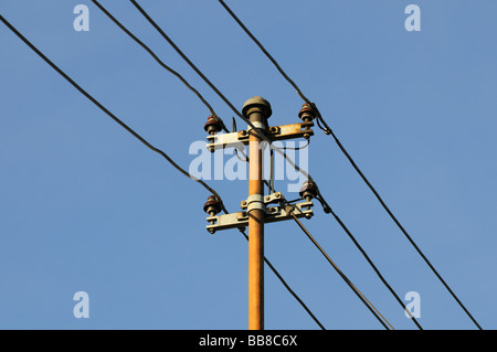 Vista di una vecchia casa polo utilità con 4 fili e isolatori ceramici di fronte a un cielo blu, alimentazione Foto Stock