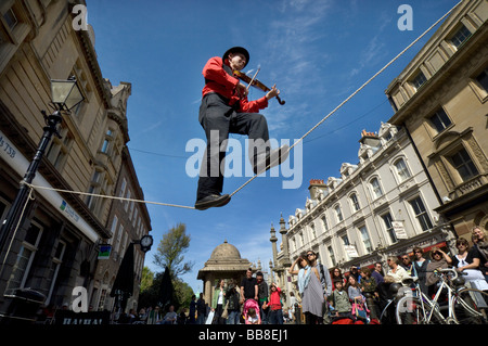 Un teatro di strada busker suona un violino mentre in equilibrio su una fune durante il Festival di Brighton Foto Stock
