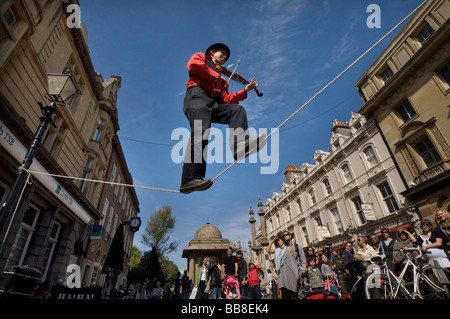 Un teatro di strada busker suona un violino mentre in equilibrio su una fune durante il Festival di Brighton Foto Stock