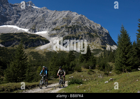 Mountainbike riders, maschio e femmina tra Karwendelhaus, alpine club house e Kleiner Ahornboden distretto forestale, Hinterri Foto Stock