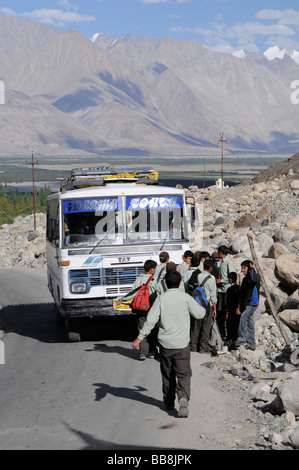 Gli studenti indossano uniformi di salire sul bus di scuola in Hunder, Valle di Nubra, India, l'Himalaya Foto Stock