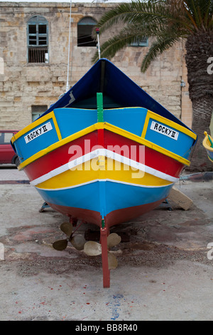 Maltese tradizionale barca da pesca, chiamato Luzzu, in piedi a terra per la manutenzione, porto di Marsaxlokk, Malta, Europa Foto Stock