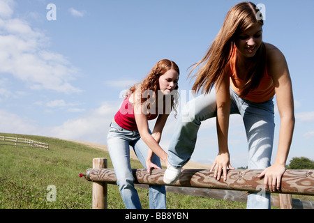 Due teenager sono scalate una recinzione su un campo Foto Stock