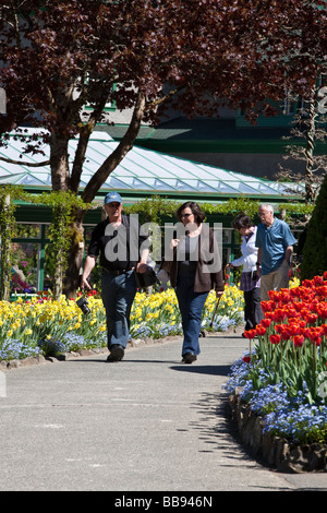 I turisti a passeggio tra fiori che sbocciano soleggiata giornata di primavera in Butchart Gardens Victoria BC Canada Foto Stock