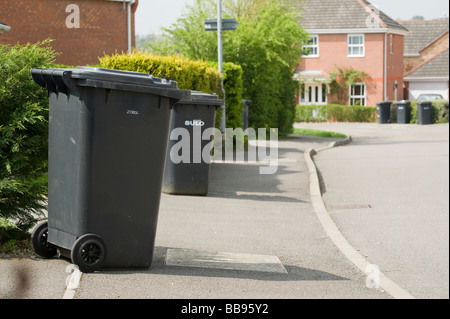Il nero della spazzatura scomparti wheelie è in attesa di essere raccolti su di una strada in Inghilterra Foto Stock