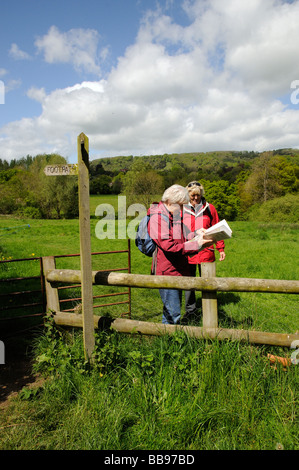 Camminatori femmina escursioni attraverso un campo stop per visualizzare una mappa Foto Stock