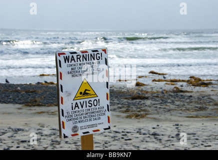 Segno sulla spiaggia avviso di persone di possibile contaminazione di acqua oceanica. Segno è scritto in inglese e in spagnolo. Foto Stock