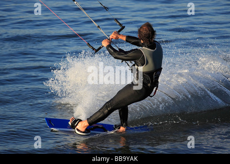 Il kite surf. Kite Surfer creando enormi scia che si muovono velocemente in cima all'acqua. Foto Stock