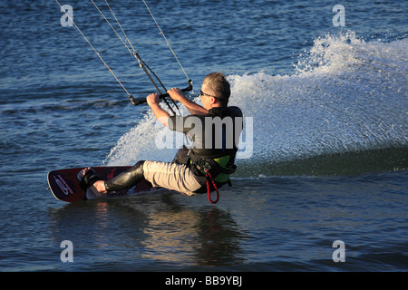 Il kite surf. Kite Surfer creando enormi scia che si muovono velocemente in cima all'acqua. Foto Stock