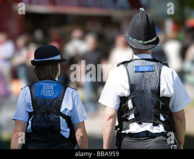 Comunità ufficiale di polizia con un poliziotto a piedi attraverso la folla al fair che mostra le etichette di polizia in gallese e il Galles Inglese UK Foto Stock