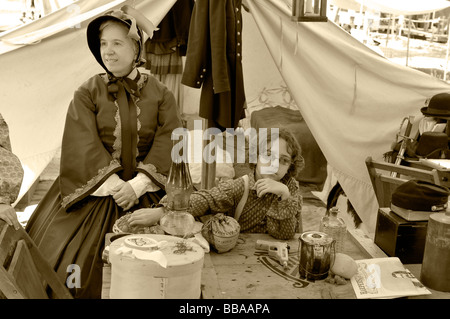 La guerra civile - Famiglia encampment ri-creazione - una donna e bambino al tavolo per la cena accanto a una tenda. I toni seppia. Foto Stock