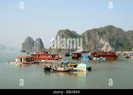 Villaggio galleggiante con case galleggianti di fronte le isole della roccia, la baia di Ha Long, Vietnam, sud-est asiatico Foto Stock