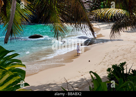 La donna a piedi lungo la spiaggia che indossa una tunica Mahe Island, Seychelles, Oceano indiano, Africa Foto Stock