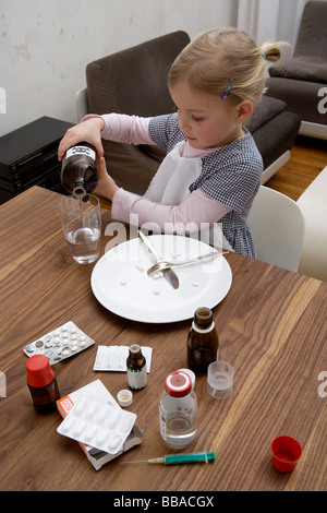 Una giovane ragazza di colare una sostanza tossica in un bicchiere e circondato da farmaci Foto Stock
