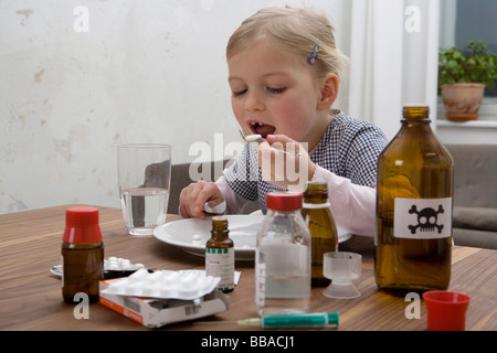 Una giovane ragazza di mangiare una pillola circondato da farmaci Foto Stock