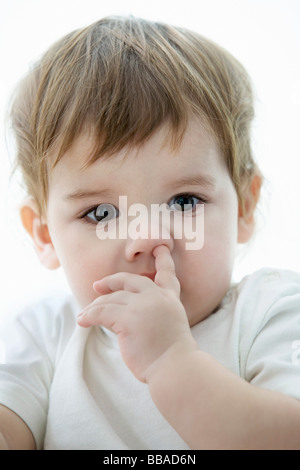 Un ragazzo giovane con un suo dito in alto il suo naso Foto Stock