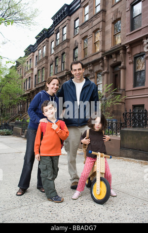 Una famiglia in piedi di fronte a una fila di case cittadine arenaria di Brooklyn, a New York City Foto Stock