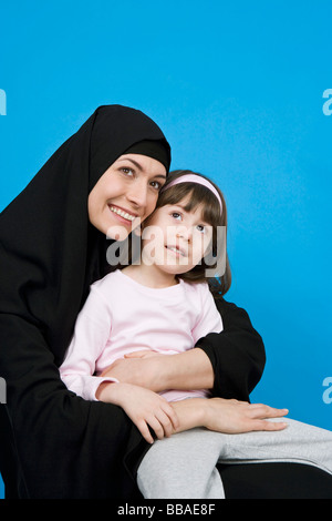 Una donna che indossa un hijab e tenendo la figlia sul suo giro Foto Stock