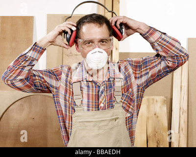 Un uomo mettendo su indumenti da lavoro protettiva Foto Stock