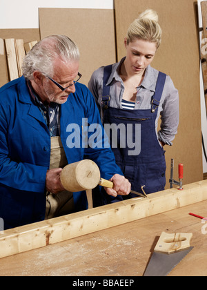 Un uomo a dimostrazione del cesello di legno di una donna in un workshop Foto Stock