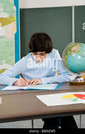 Uno scolaro funzionante a una scrivania Foto Stock