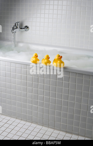 Un bagno di bolle con le papere di gomma sul lato della vasca Foto Stock