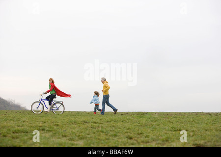 Un ragazzo e un uomo a caccia di una donna in sella a una moto Foto Stock