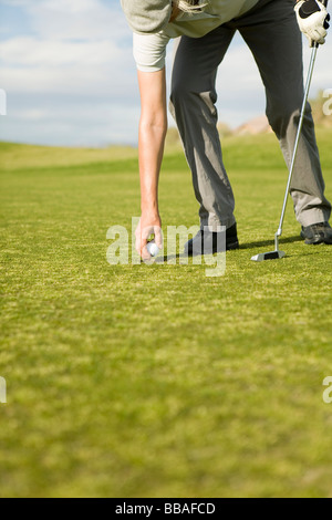 Una donna mettendo una pallina da golf su un raccordo a T Foto Stock