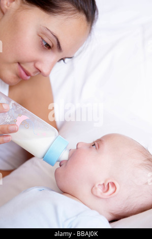 Madre dando la bottiglia al suo bambino Foto Stock