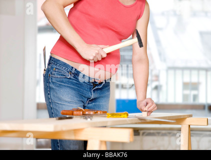 Donna incinta con il martello e il chiodo Foto Stock