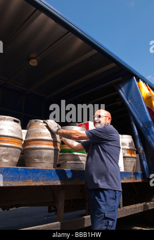 Un birrificio Adnams lavoratore personale lo scarico e la consegna di ale e birra al pub dal retro di un camion nel Suffolk, Regno Unito Foto Stock