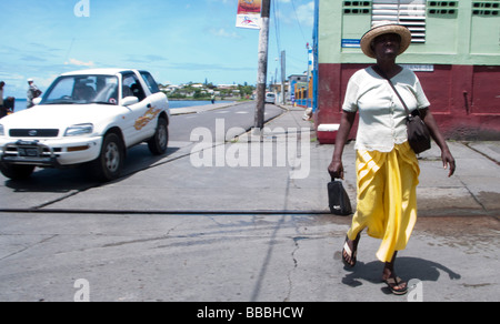 La donna residente locale nel cappello di paglia a camminare sulla strada della baia di capitale Basseterre St Kitts Foto Stock