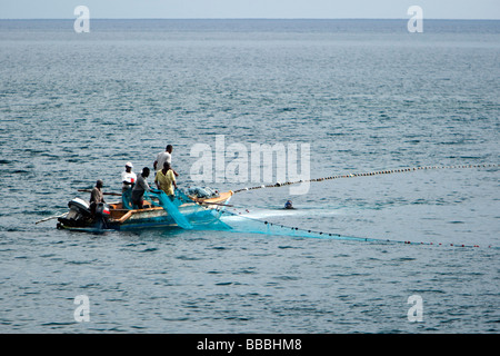 I pescatori locali alaggio rete da pesca su piccola barca su St Kitts dei Caraibi Foto Stock