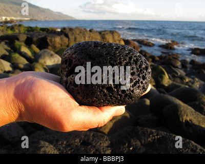 Mano che tiene la pietra lavica, sulla costa a La Palma Isole Canarie Spagna Foto Stock